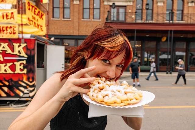 A woman enjoying a funnel cake at Main Street Fest in Grapevine, Texas